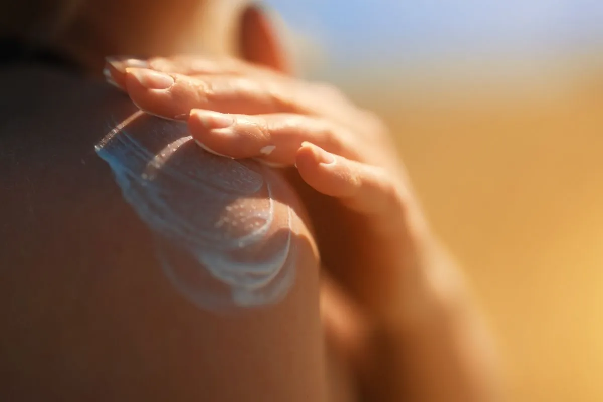 woman applying sunscreen on shoulder